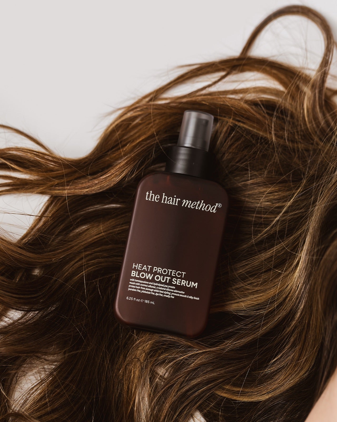 The Hair Method serum resting on long brown hair