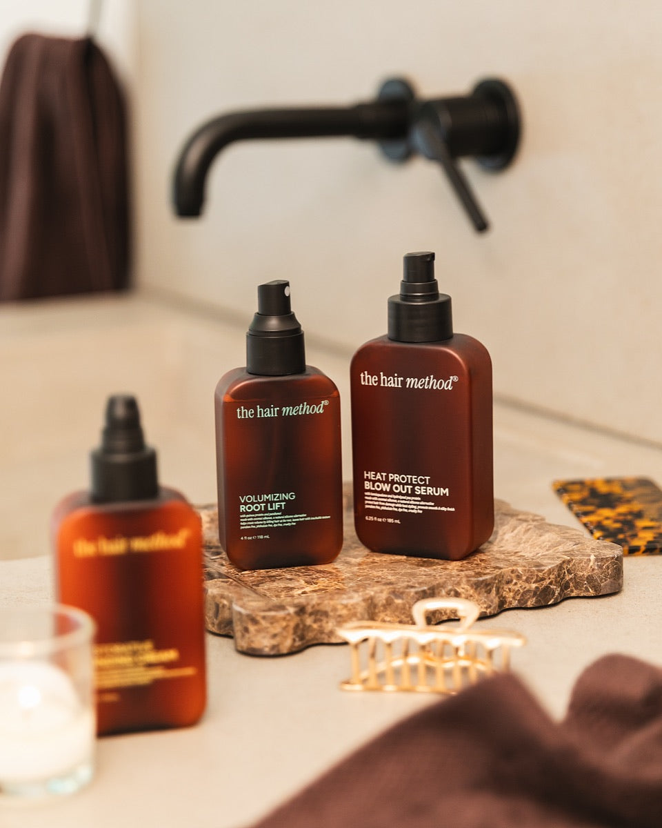 The Hair Method bottles on a stone tray by a bath tap