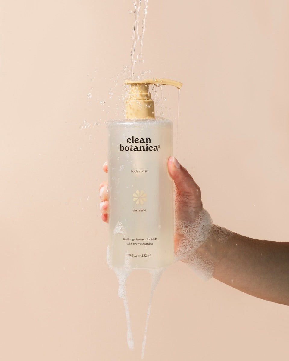 Water pouring over a Clean Botanica body wash held in a hand